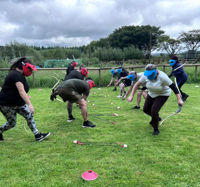 a group of people playing archery tag on a grassy field