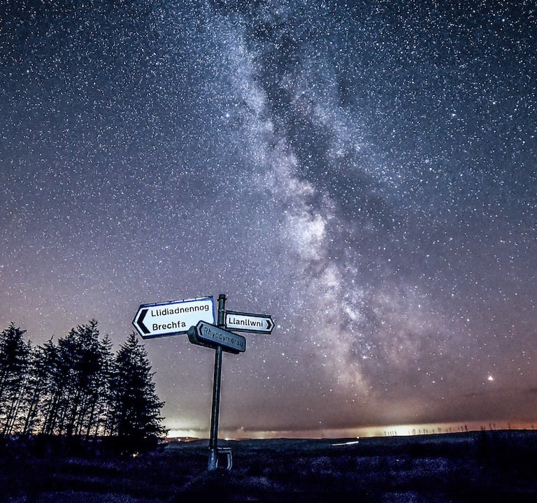 a street sign with a milky way like sky in the background