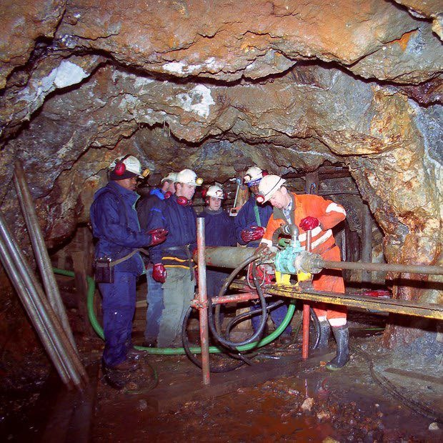 A group of people in a cave like area with old mining machinery