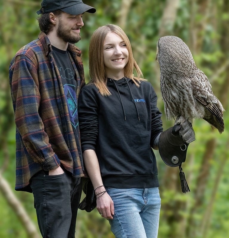 a man and woman standing next to each other with a bird of prey