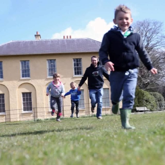 A family running in front of an historic house