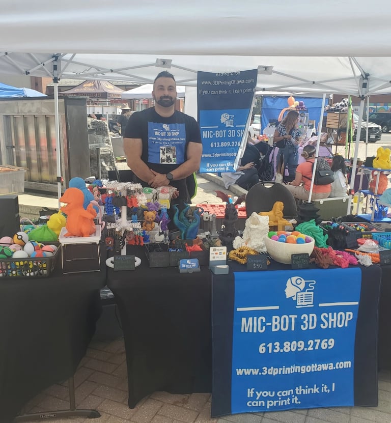 Mic-Bot standing in front of a table with a display of 3D Models