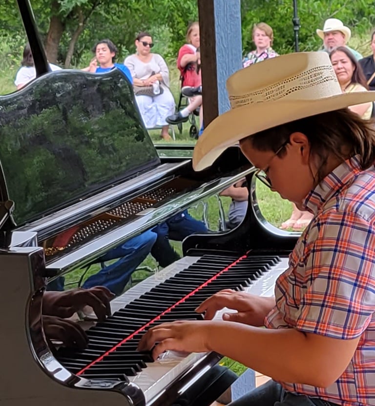 a young boy in a cowboy hat playing a piano