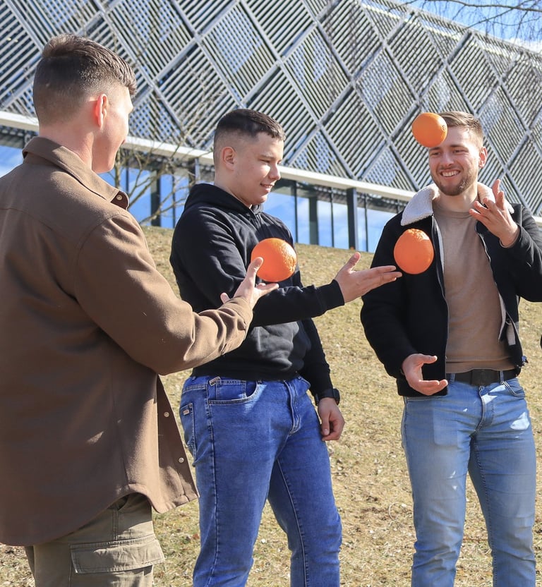 Jauni zmones lauke zaidzia su apelsinais