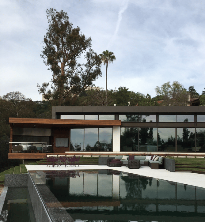 a vanishing edge pool and spa with a view of a large house