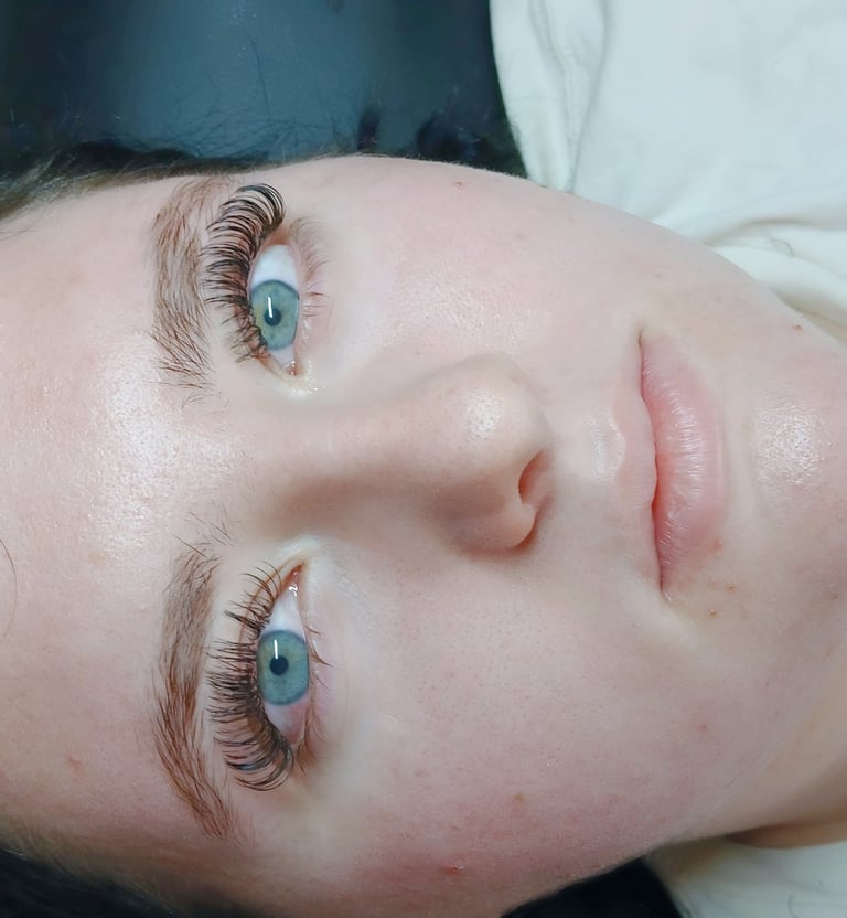 A woman with clear skin showcasing professional eyelash extensions and full lashes.
