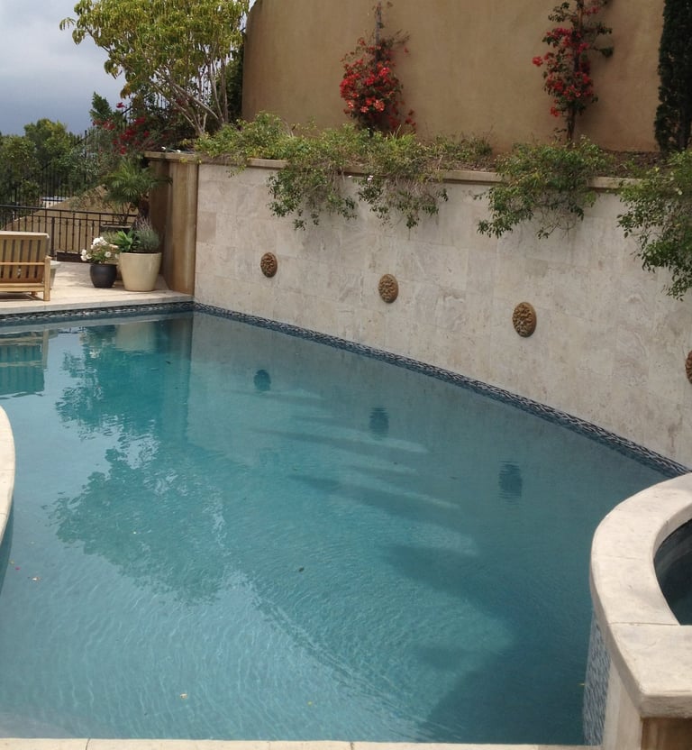 a pool with a large wall with scupper water features