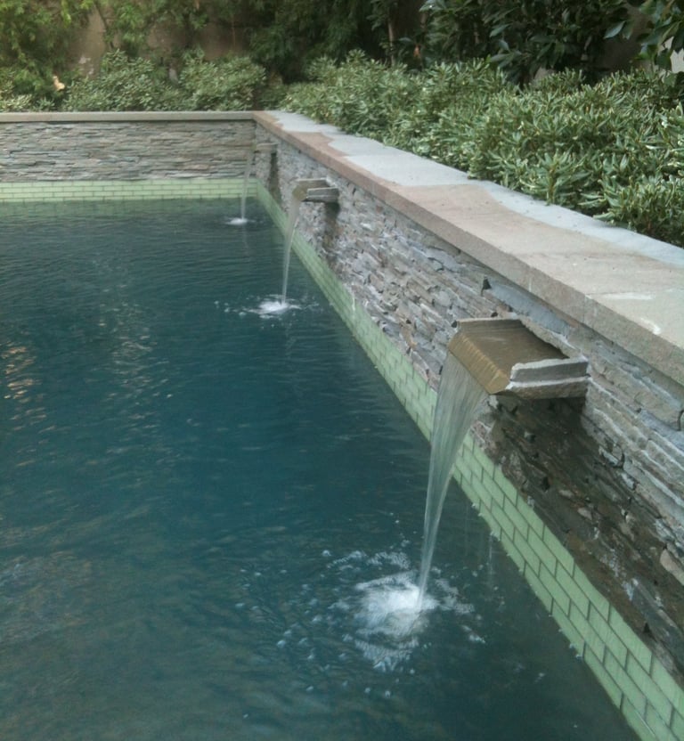 a pool with three custom stone spillways