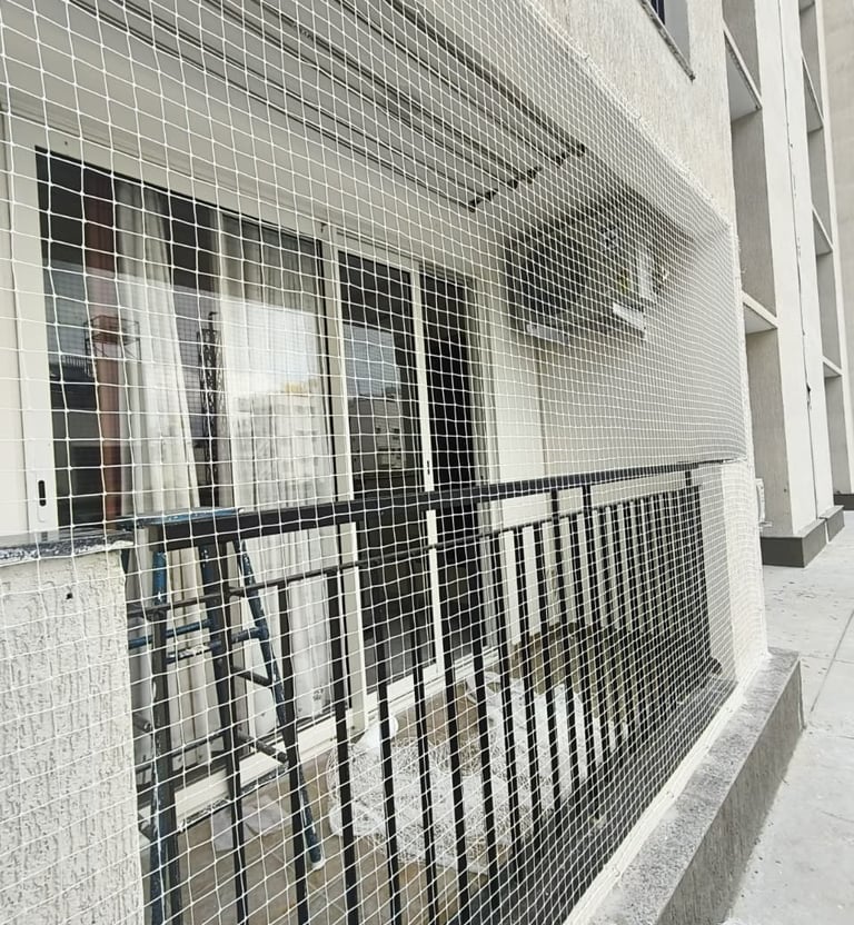 Wide view of a balcony fully covered with fine mesh pigeon netting, showing neat installation by Arj
