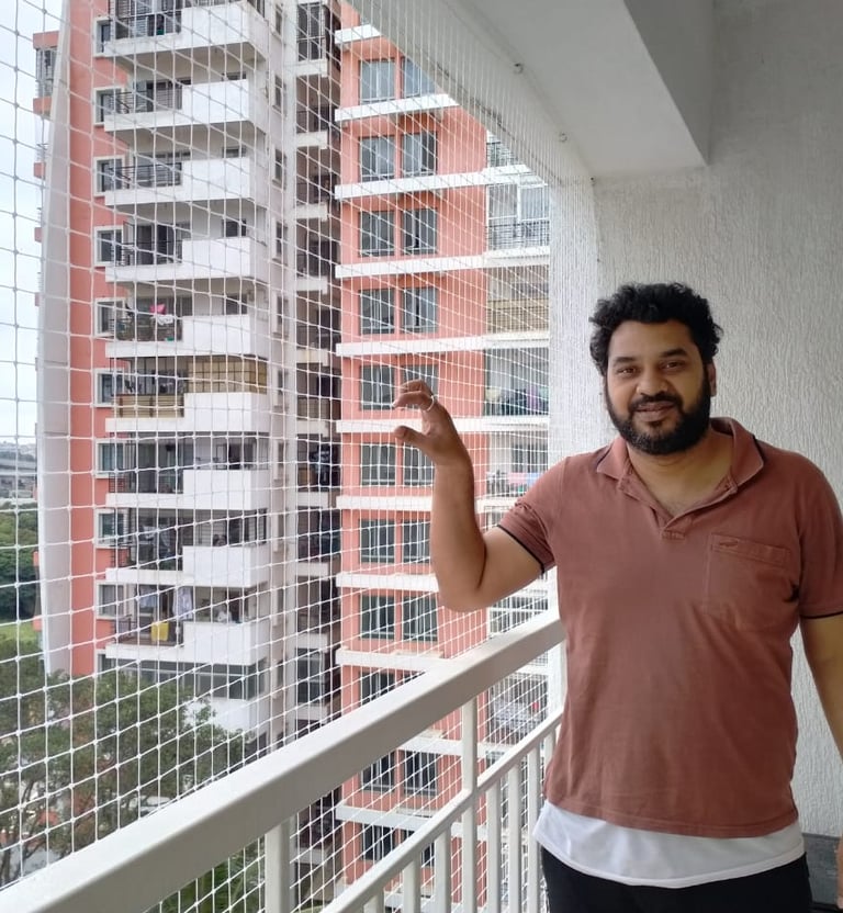 Wide-angle view of a balcony fully enclosed with safety nets, sunlight filtering through the mesh.