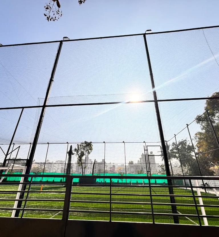 Wide shot of a baseball field with new protective nets installed behind home plate, with players pra