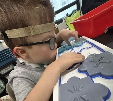DeafBlind learner focuses on tactile puzzle provided by DUAL Tools Initiative