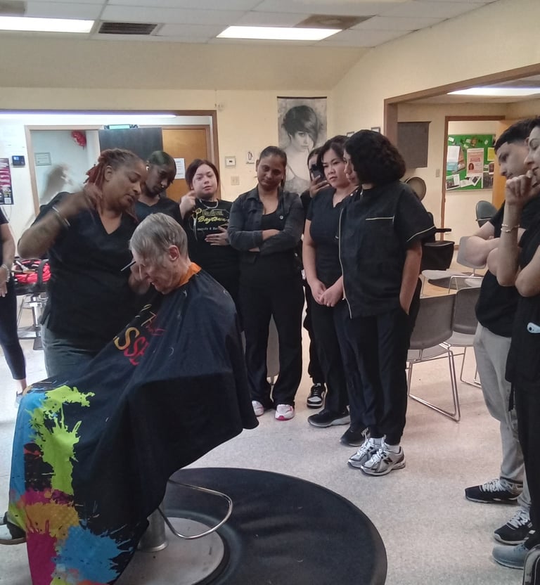 A group of cosmetology students observing a hair cutting demonstration in a salon classroom environment.