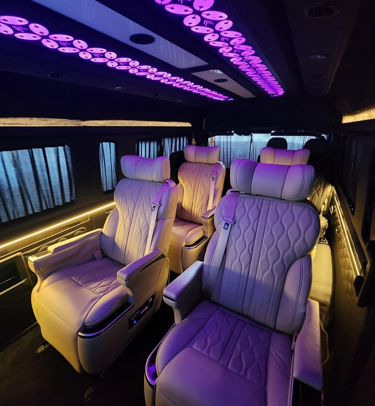 Luxury Premio van interior with leather reclining seats and purple LED ceiling lights.