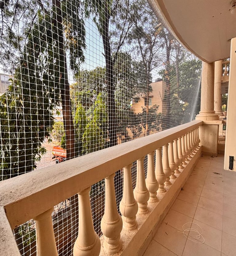 Wide shot of a high-rise apartment balcony fully covered with a transparent safety net to keep pets 