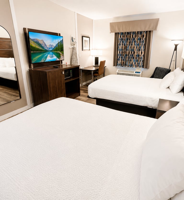 Modern hotel room with two queen beds, a flat-screen TV, desk, and full-length mirror.