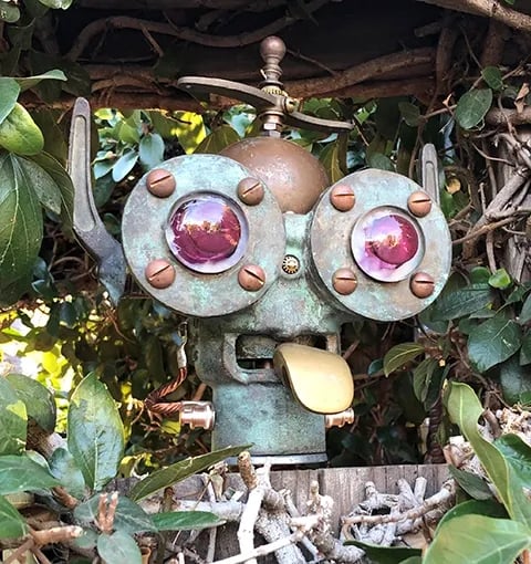 Robot head in hedge sticking out his tonguel