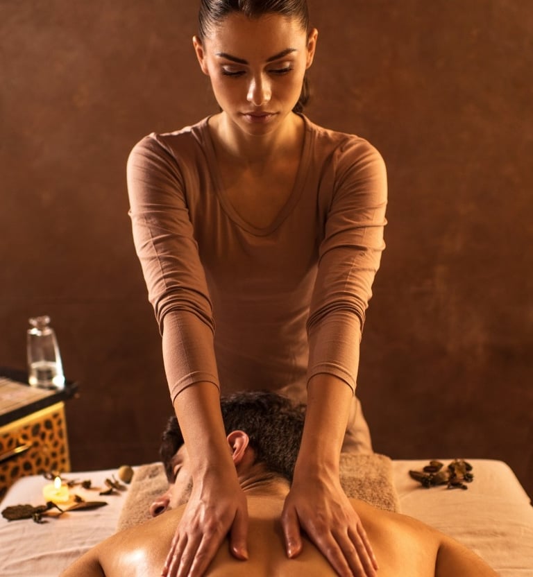 Terapeuta profesional realizando un masaje relajante con aceites en la espalda de un hombre