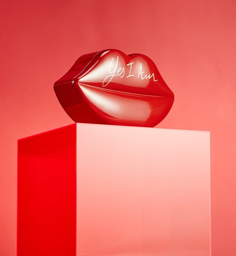 Product Photography of a bold lips-shaped perfume bottle on a vibrant red backdrop, using glossy tex