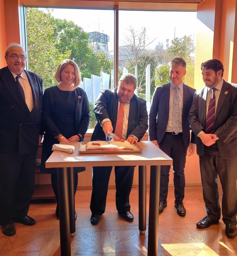 a group of people standing around a table with a cake