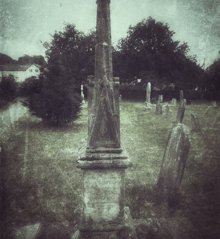 Vintage-style photo of an old stone obelisk monument and headstones in a historic graveyard.