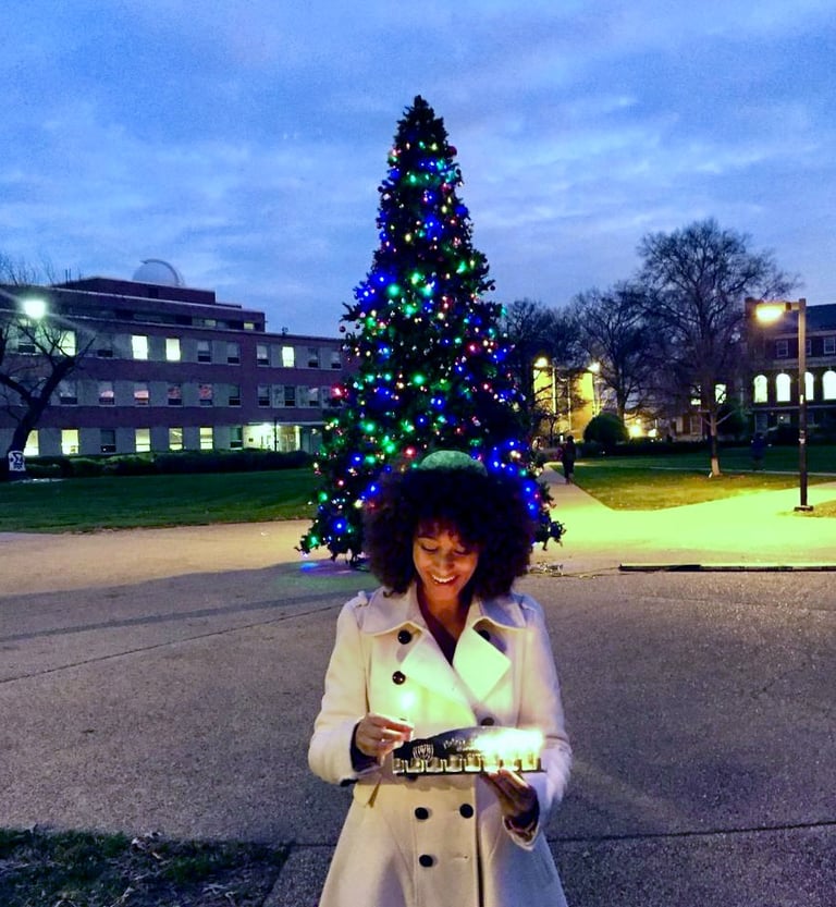 Howard University alum, Rebecca Franklin, lighting the hannukiah in front of campus Christmas tree