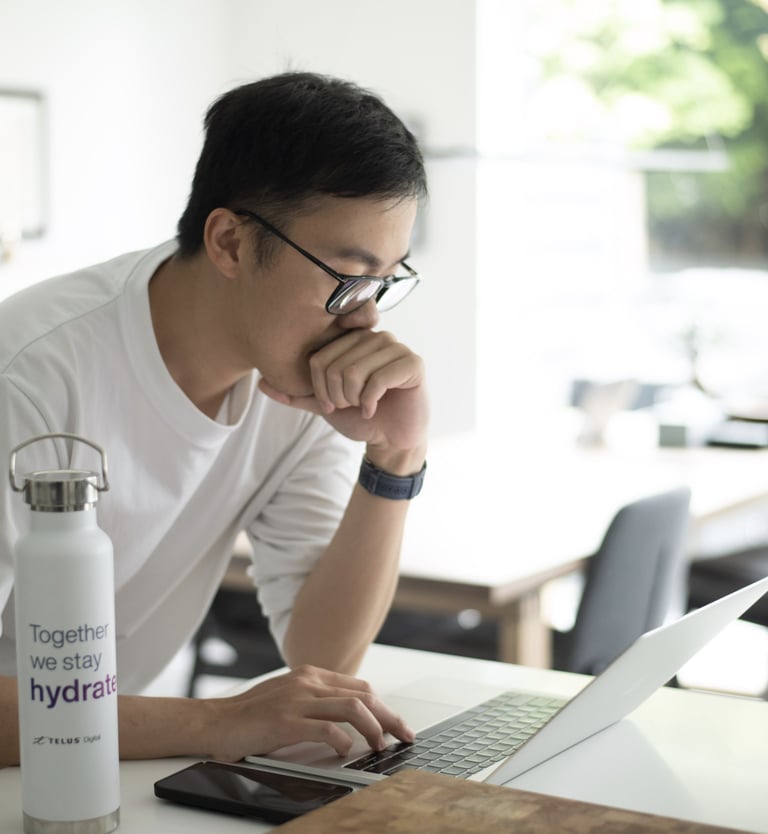 a man sitting at a table with a laptop and a water bottle