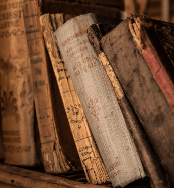 Aged books leaning against one another on a shelf