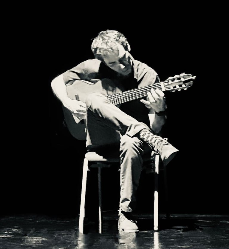 Paco tocando la guitarra bajo una luz cenital de teatro.