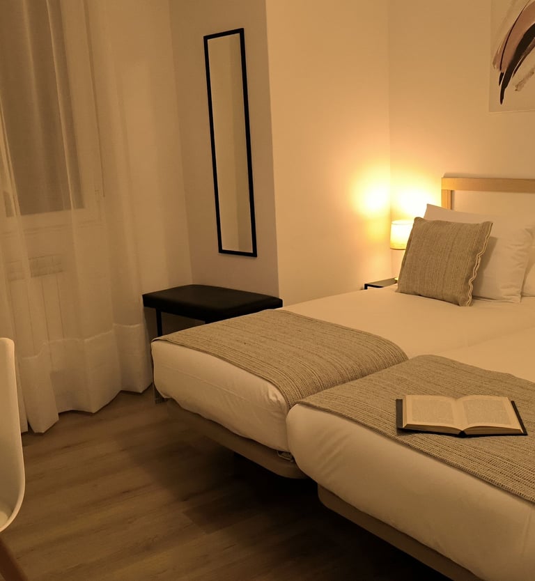 Habitación doble en Hotel Arias, Vigo, con escritorio y luz de mesilla encendida