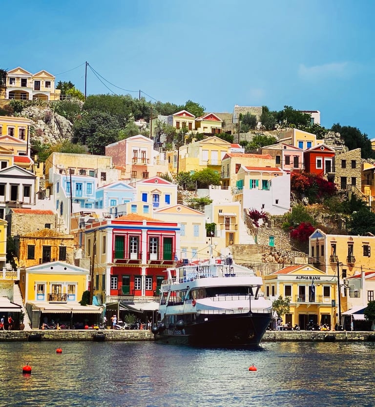 a boat in the water near a bunch of colorful buildings in SYMI island