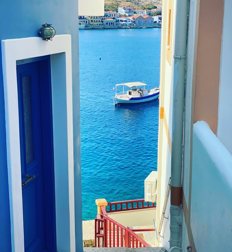 a boat on water with picture taken between houses in Chalki island