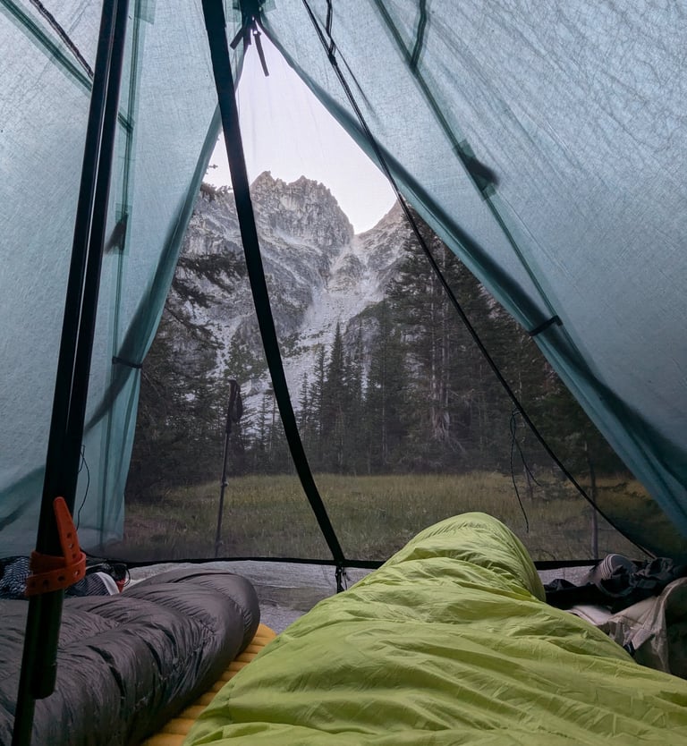 View of a jagged mountain peak and forest from inside a the Hyperlite Ultamid 2 with sleeping bags.