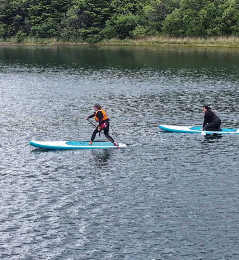 A paddle board coach demonstrating a step back turn to a student
