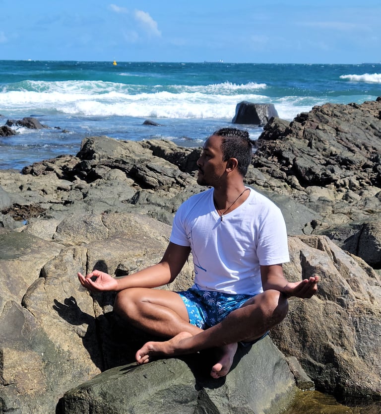 Wil in meditative pose near the ocean on rocks