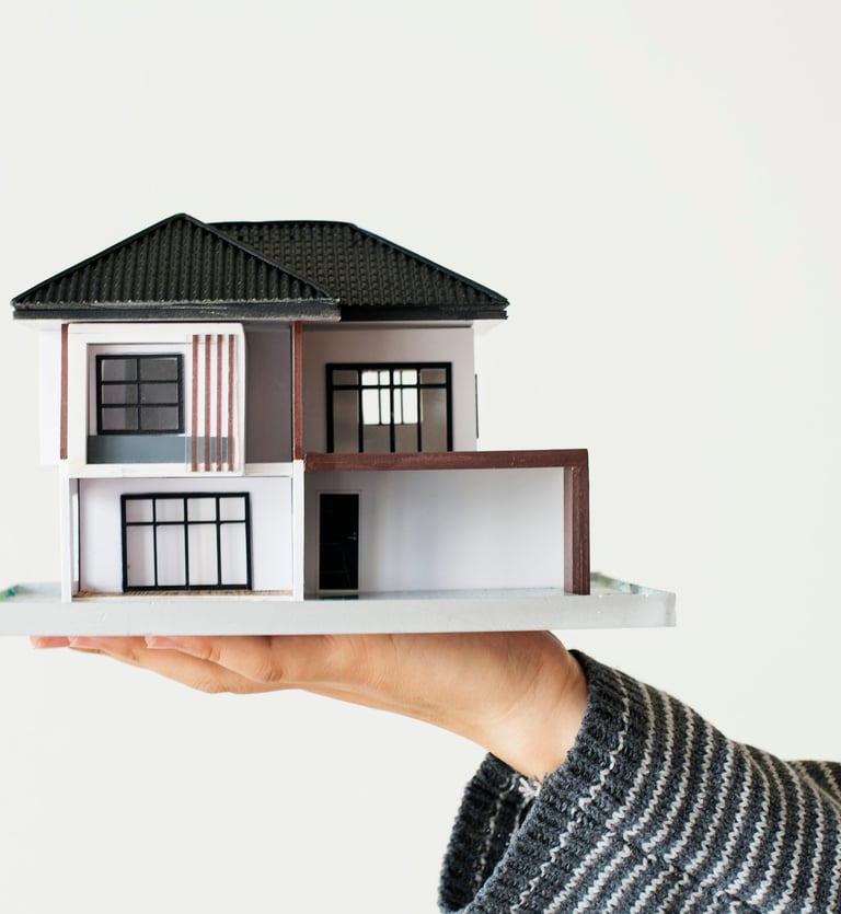 Een persoon die een klein model van een huis vasthoudt.