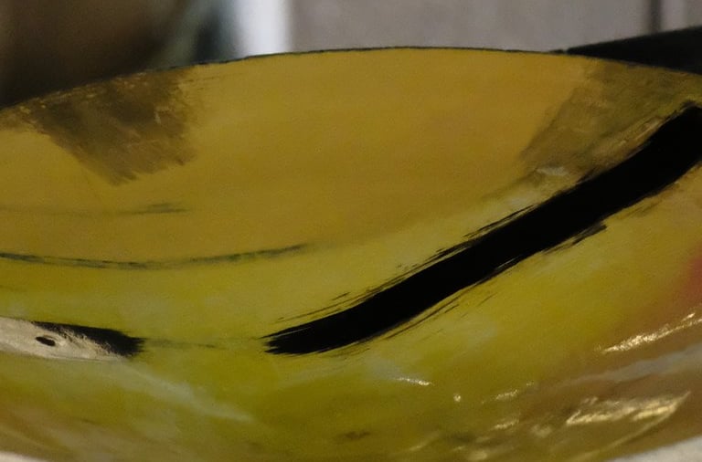 A wide low thrown ceramic bowl in white stoneware. Inside is painted with oxides and gold lustre 