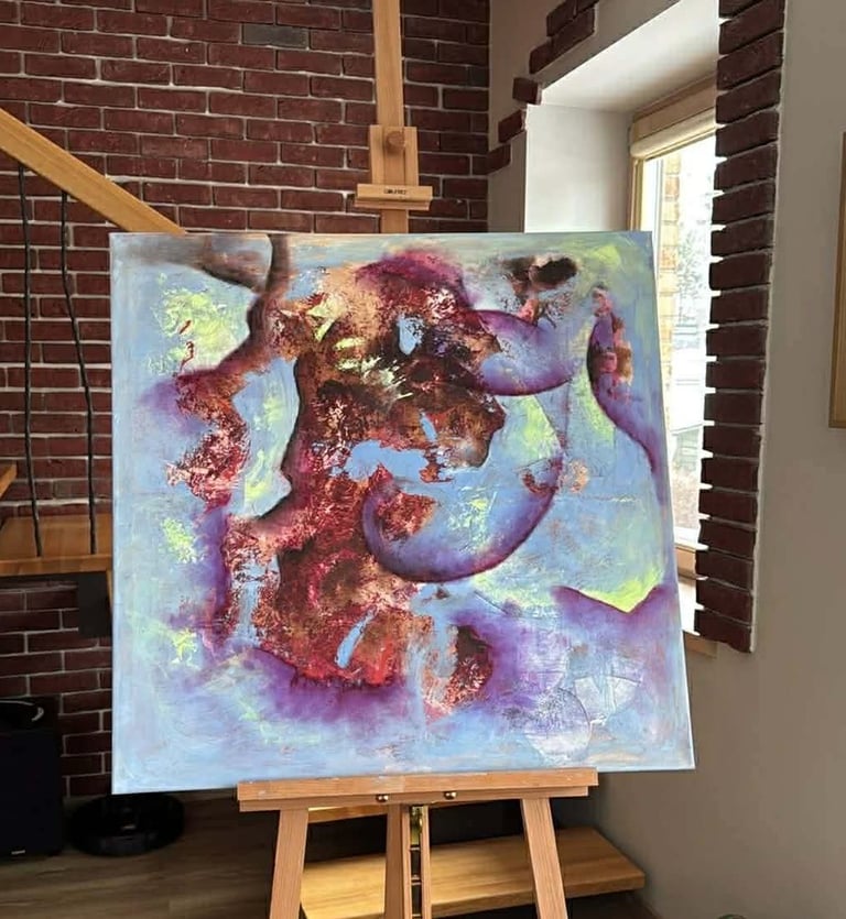 Modern abstract canvas painting with purple and blue hues on a wooden easel in an art studio.