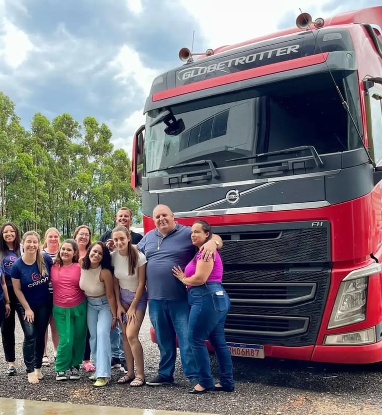 Equipe da Caran Contabilidade junto aos parceiros da Xandão ao lado de caminhão vermelho.