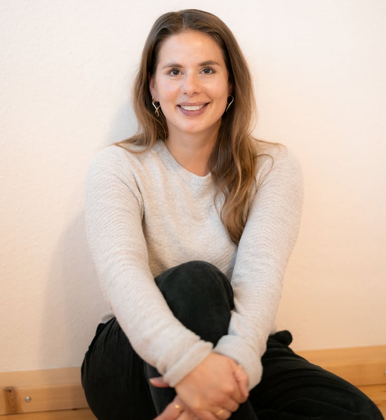 Eine Frau, mit verschränkten Beinen auf dem Boden sitzend. Stressmanagement Beratung.