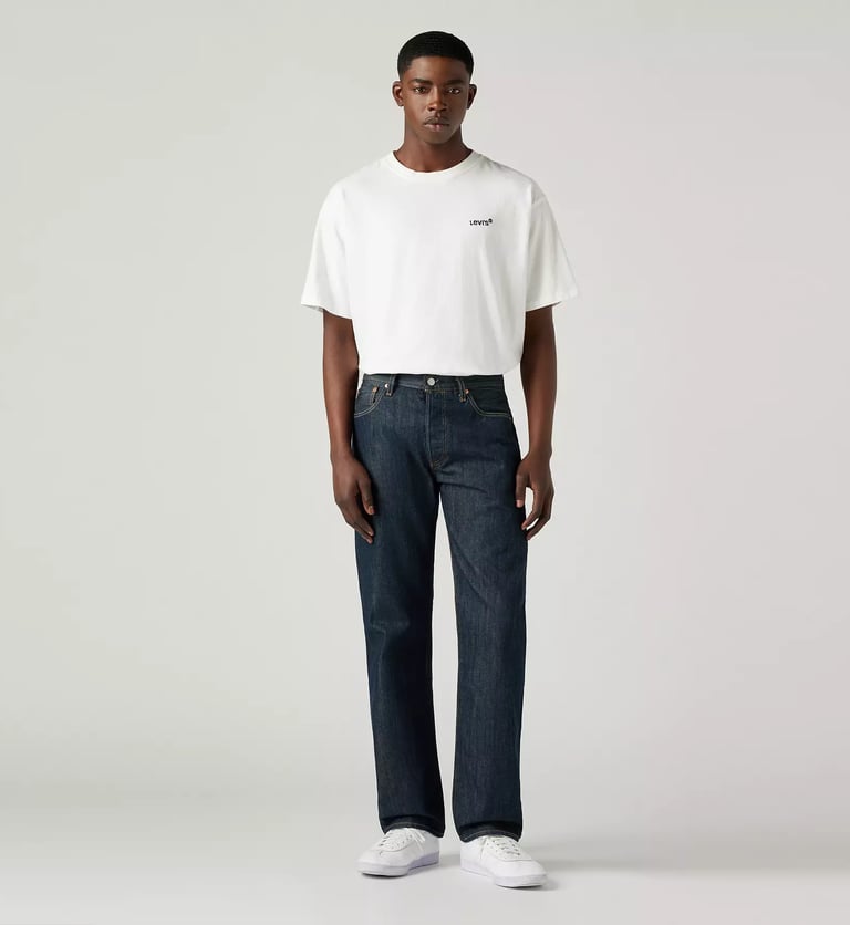 Male model wearing Levi’s 501 Jeans in dark indigo, paired with a white t-shirt and sneakers.