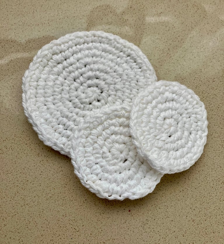 3 round white crocheted face scrubbies lying on each other