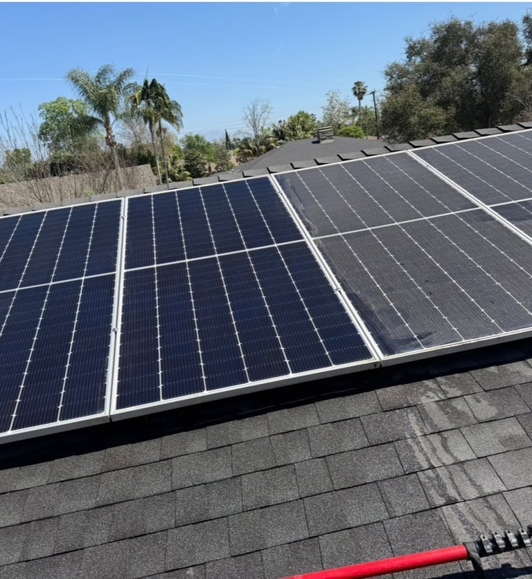 Residential solar panel installation on a dark shingle roof with a clear blue sky background.