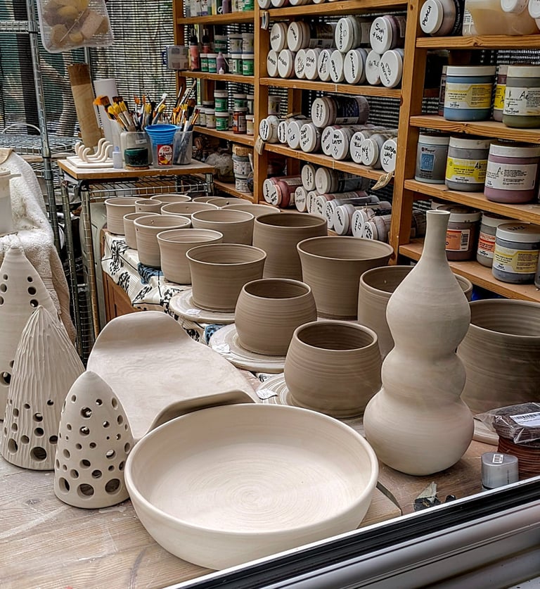 Pottery in production in the GonPotty studio with glazes and tools in the background