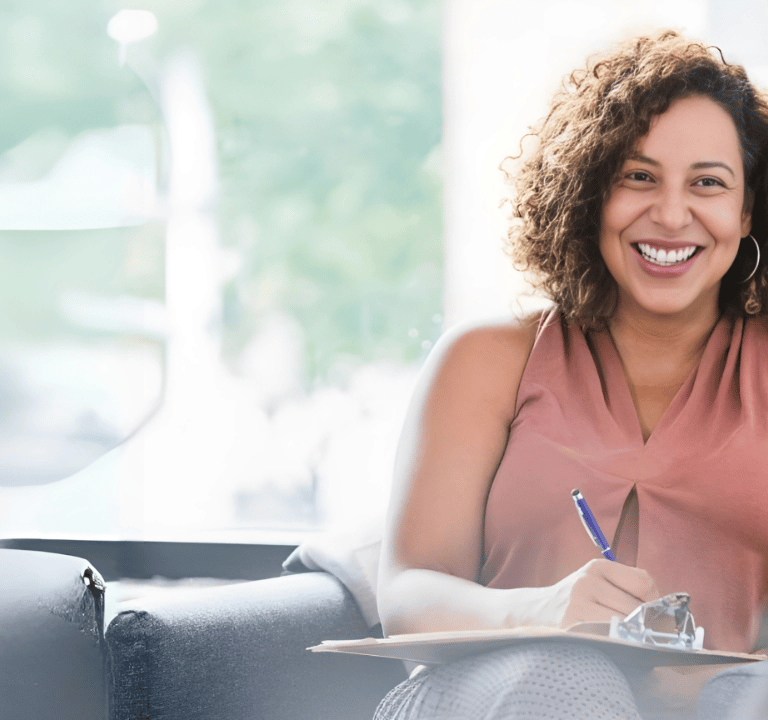 a woman sitting on a couch with a pen and a notebook