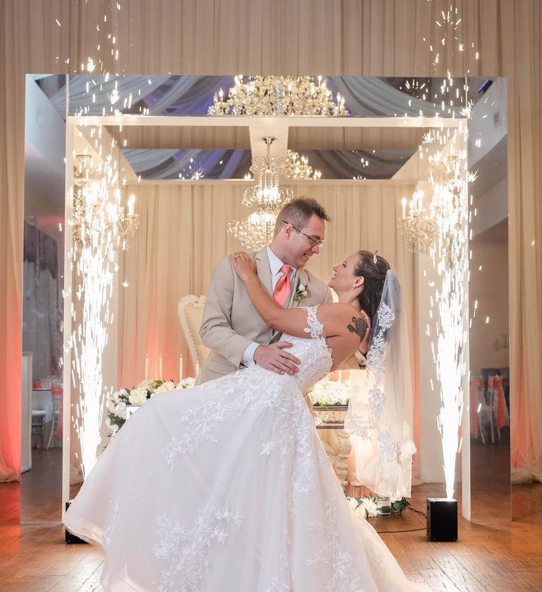 Newlywed couple's first dance featuring indoor sparkler fountains and elegant chandeliers.