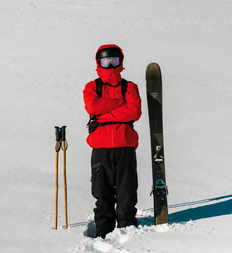 Baptiste Rouge bras croisés avec les batons de ski en bambou a sa droite et ses skis à sa gauche