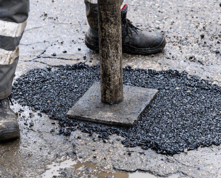 Stamping down asphalt pothole repair on roadway