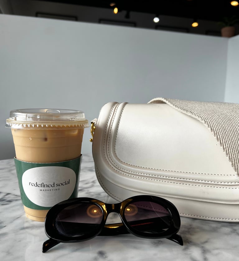 a white purse with sunglasses and a coffee cup