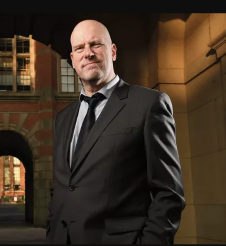 David Gillborn in a suit and tie standing in front of a building